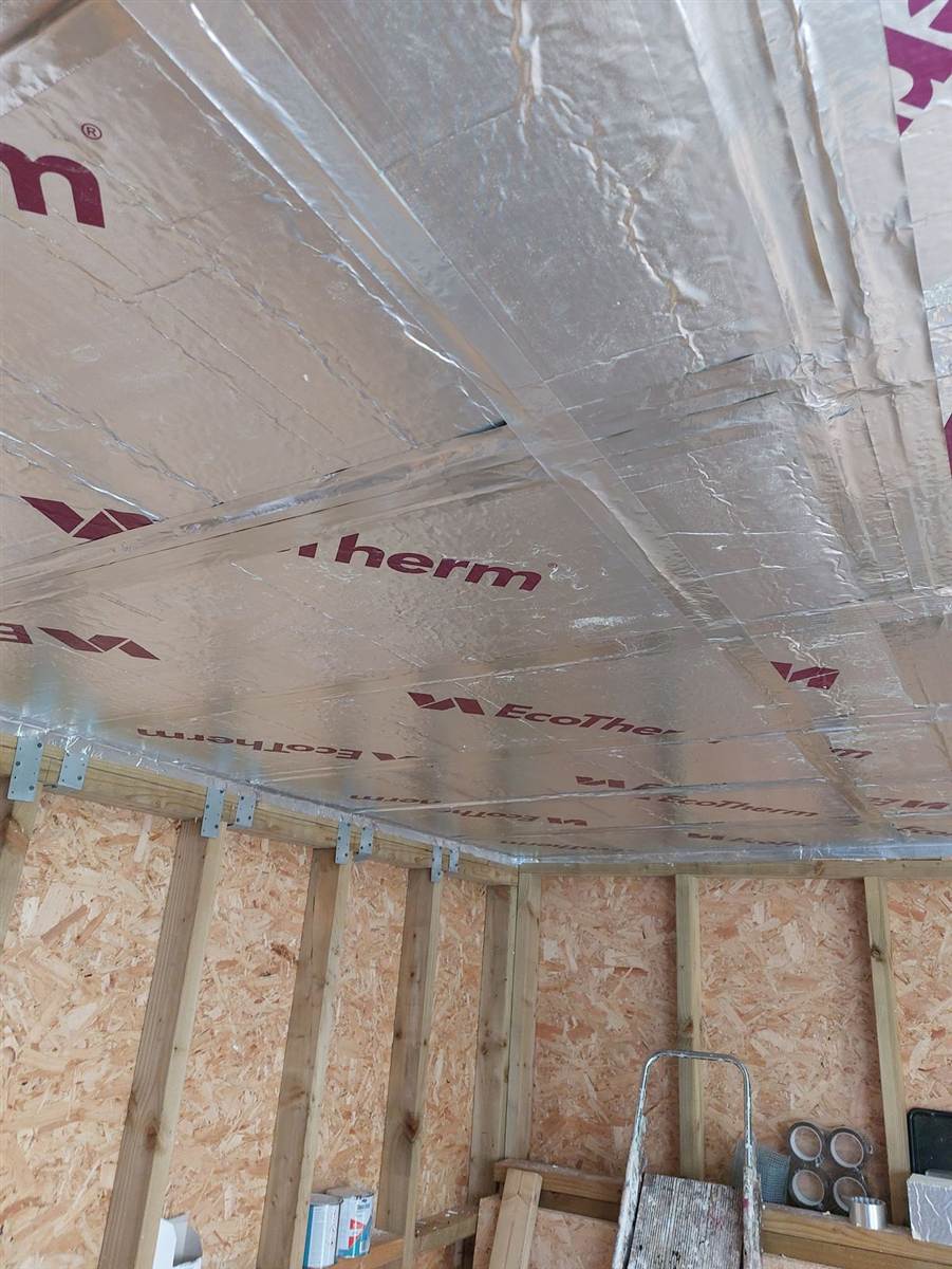 EcoTherm rigid insulation boards cut and fitted tightly between roof joists, viewed from inside